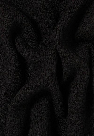 Tessuto nero strutturato con un motivo a maglia morbido che mostra pieghe e ombre dettagliate.