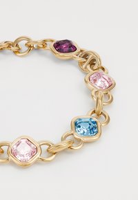 Gold chain bracelet featuring four rectangular stones: deep purple, soft pink, light pink, and blue. Smooth, shiny texture with interlocking links.