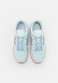 Light blue athletic shoes with mesh and synthetic upper, lace-up design, and rubber outsole. Features silver accents and "NB 500" branding.