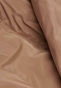 Tissu marron, semblable à du satin, avec une texture lisse ; présente des plis doux et fluides ainsi qu'un éclat subtil ; semble léger et flexible.