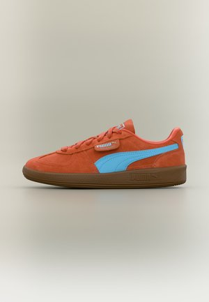 Baskets Puma Palermo en daim orange avec une bande bleue, une semelle marron et des lacets, vues de profil sur un fond neutre.