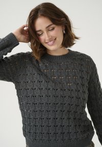 Maglione grigio lavorato a maglia con un motivo aperto largo, collo rotondo e polsini a costine. Texture morbida, che offre una vestibilità comoda e un design traspirante.