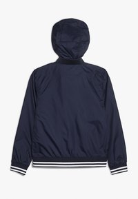 Giacca cappuccio blu navy con polsini e orlo elastici, caratterizzata da rifiniture a righe bianche e blu navy, mostrata dal retro su uno sfondo bianco.