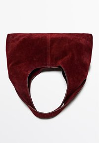 Bordowa torba tote z zamszu z otwartym wierzchem, unikalnymi uchwytami w kształcie wycięcia i gładkim wykończeniem. Posiada wzmocnione szwy wzdłuż krawędzi.