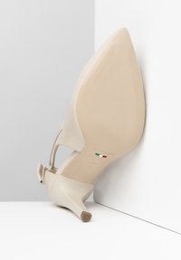Scarpa con tacco alto beige con punta appuntita, tomaia in tessuto morbido e tacco sottile. Presenta un logo e un'etichetta per la taglia sulla suola.
