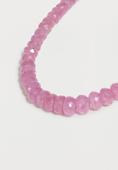 Σειρά από στρογγυλές ροζ χαντρες με όψη, σε διάφορες αποχρώσεις, τοποθετημένες στενά σε ανοιχτό φόντο.