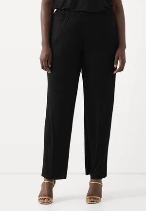Pantaloni neri leggeri con una vita elastica, caratterizzati da un design a gamba dritta. Abbinati a sandali dorati con cinturini.