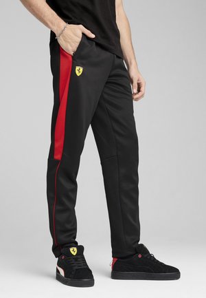 Pantaloni atletici negri cu o dunga roșie pe lateral și un logo galben Ferrari. Material neted, cu o croială lejeră și buzunare laterale funcționale.