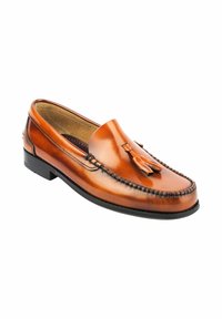 Mocasín de cuero marrón con acentos de borlas, costura estilo mocasín en la parte delantera y suela de goma negra. Textura suave y forma redondeada.