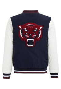 Laikku- ja valkoinen pommittaja-takki, jossa on teksturoitu punainen ja valkoinen brodeerattu tiikerin pää takana, sekä raidalliset resorit hihoissa ja kauluksessa.