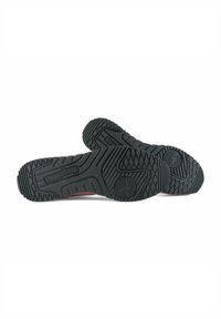 Suole di scarpe in gomma nera con un motivo testurizzato, caratterizzate da scanalature e il logo del marchio impresso. La costruzione sembra resistente e aderente.