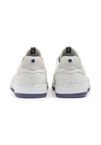 Sneakers bianchi in pelle con accenti grigi testurizzati, una forma tondeggiante, suole blu scuro a contrasto e linguette nere sul tallone.
