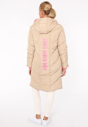 Beige Steppjacke mit Kapuze, versehen mit pinkem "GOOD VIBES ONLY"-Schriftzug und kontrastierenden pinken Akzenten. Gequiltes Design mit langen Ärmeln.