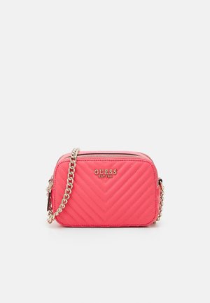 Lille rektangulær lyserød quiltet crossbody taske med en guldkæde og "GUESS EST 1981" logo foran.