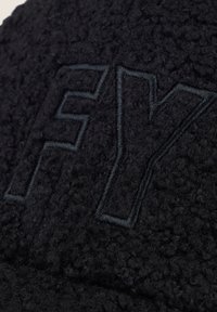 Cappello di pile nero con tessuto testurizzato, grande logo ricamato "FY" in una tonalità scura a contrasto e design strutturato.
