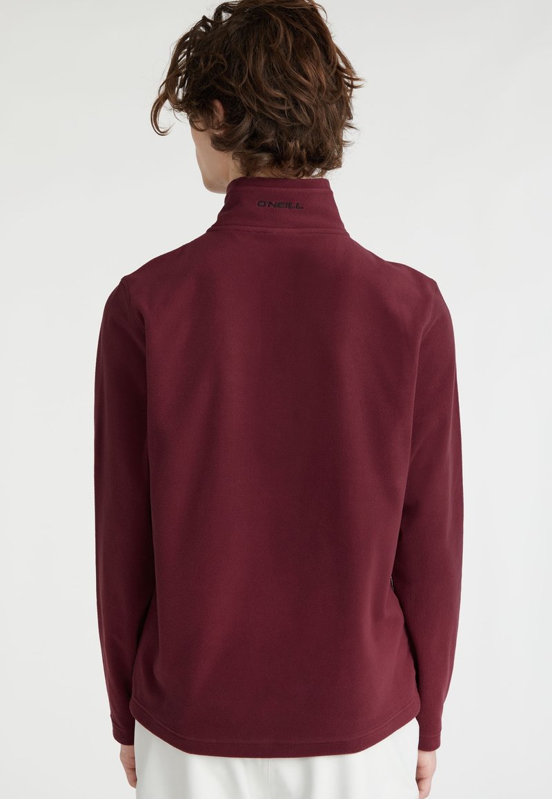 Pullover en polaire bordeaux avec un col haut, des manches longues et le logo O'Neill dans le dos. Texture douce et coupe décontractée.