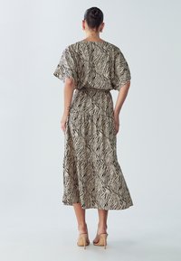 Plūstoša midi kleita ar melnu un krēmkrāsas zebras rakstu, īsām piedurknēm un kārtainu svārku dizainu. Izgatavota no viegla auduma.