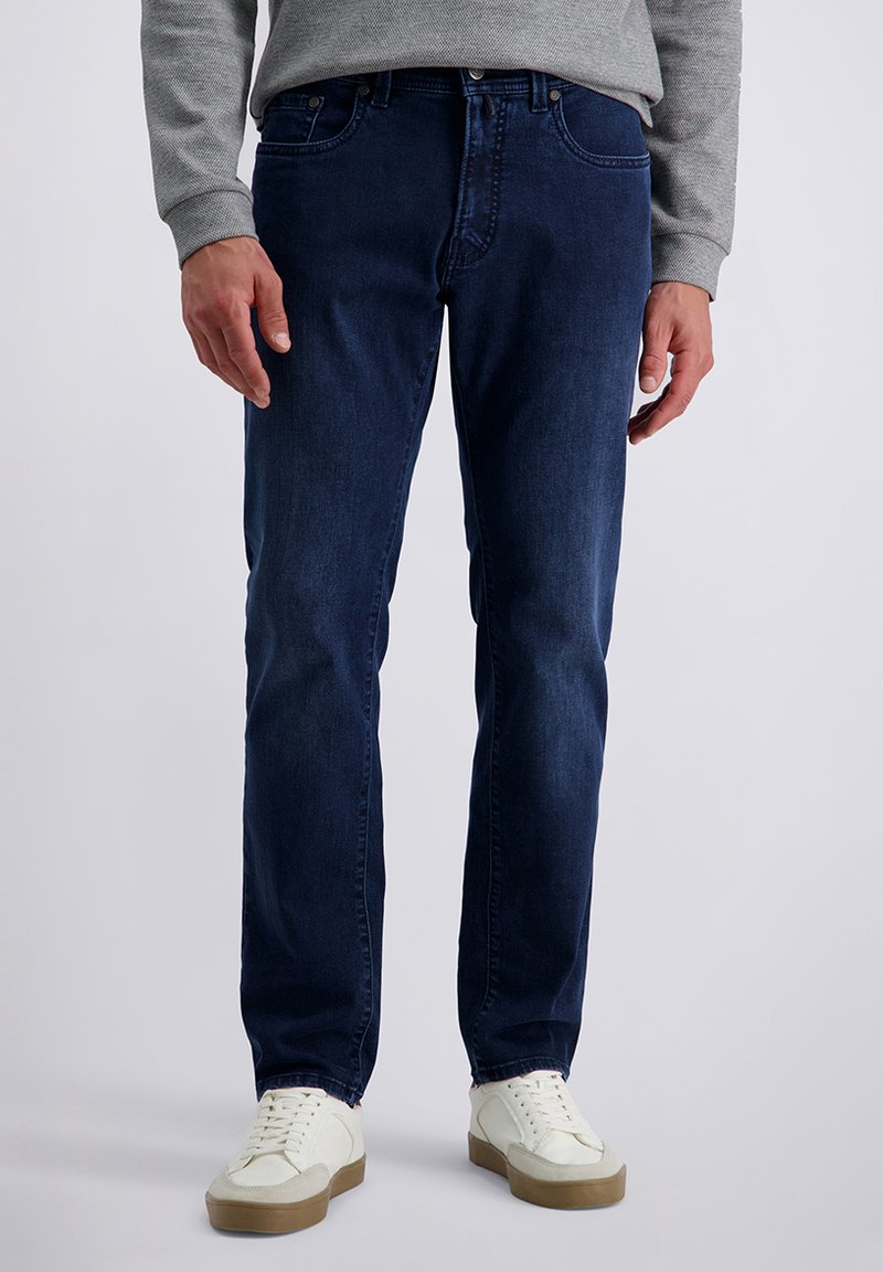 Donkerblauwe denim jeans met een rechte pijp, voorzien van steekzakken en een klassieke knoop- en ritssluiting, gecombineerd met witte sneakers.