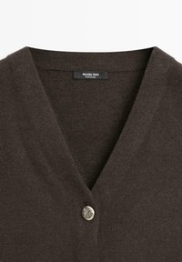 Cardigan marron foncé en tricot présentant un col en V et un bouton décoratif argenté. Le tissu semble doux avec une légère brillance.