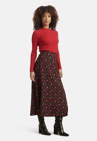 Red ribbed sweater paired with a black skirt featuring red and pink polka dots. The model wears black heeled boots.