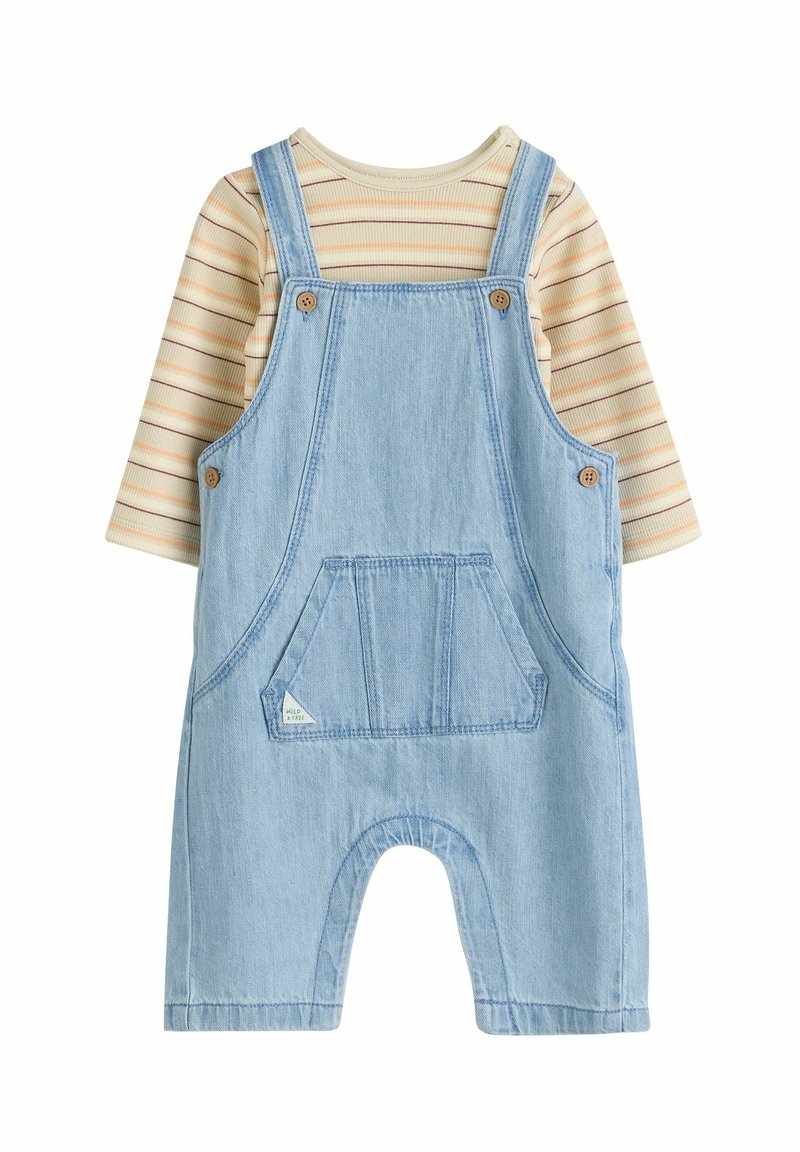 Salopette en denim bleu clair avec une poche frontale, superposée à une chemise à manches longues beige et rayée. Convient aux enfants.