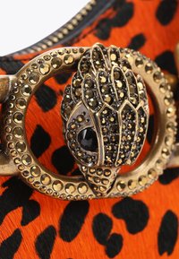 Materiale con stampa leopardata arancione e nera, dotato di una chiusura metallica con decorazioni nere e dorate, superfici testurizzate e dettagli intricati.