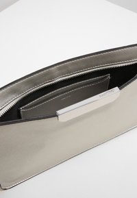Borsa a pochette in metallo argentato con texture liscia, interno nero, chiusura con zip e un'accurata finitura in argento piatta nella parte superiore.