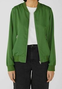 Groene bomberjack van glad nylon met een ritssluiting aan de voorkant, ribbelkraag en manchetten. Beschikt over twee zijzakken en een relaxte fit.