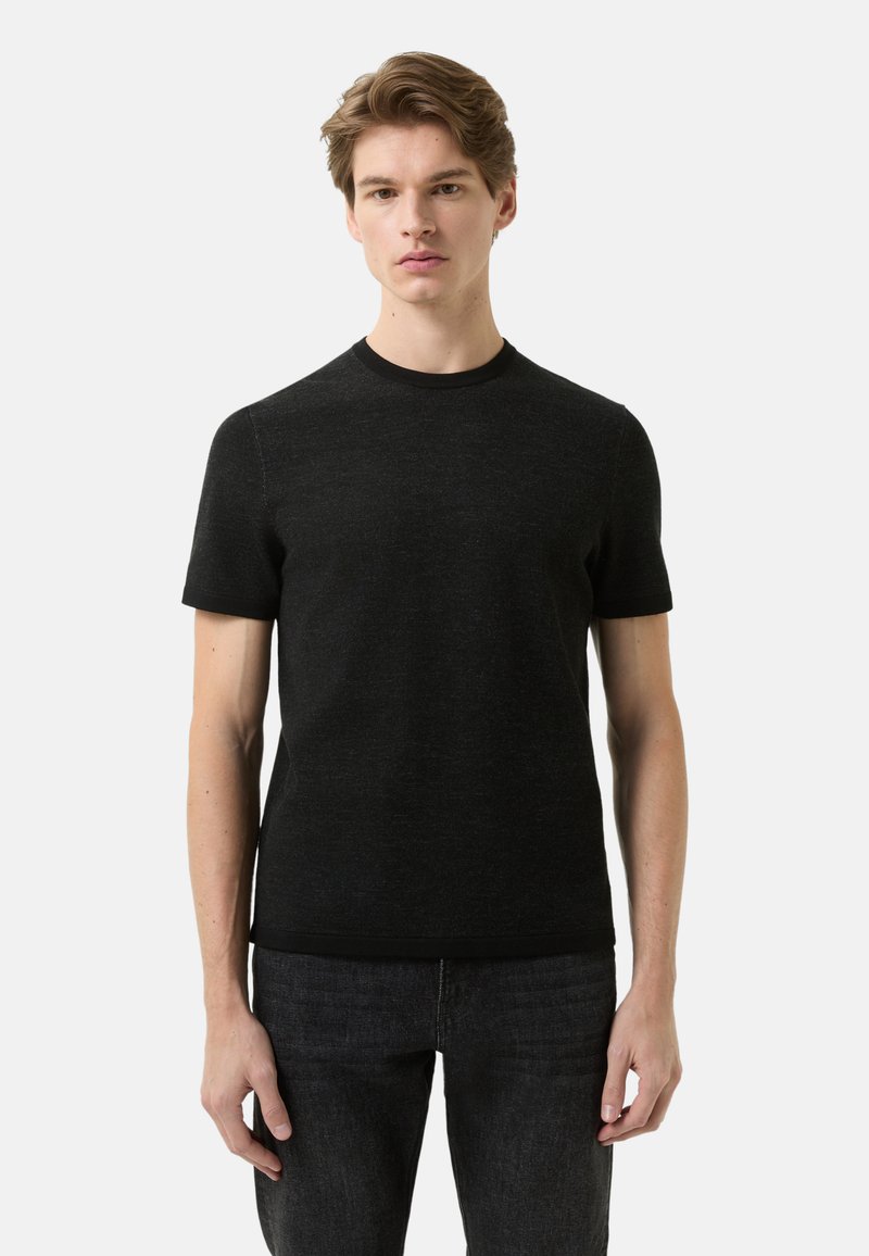 Sort t-shirt med korte ærmer lavet af blødt stof, med rund hals og glat tekstur, kombineret med mørke jeans.