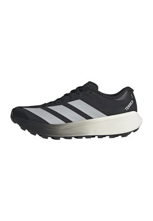 Sort-hvid Adidas Terrex trail løbesko med tyk sål og tre reflekterende striber på siden på en hvid baggrund.
