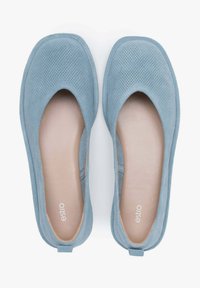 Jasnoniebieskie perforowane baleriny z zaokrąglonym noskiem i miękką suwakową fakturą. Wnętrze z gładką, beżową podszewką. Widoczna marka na podeszwie.