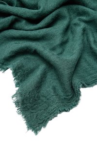 Zielony teksturowany koc, wykonany z miękkiego materiału, z frędzlami na krawędzi. Tkanina ma lekko puszysty wygląd w głębokim zielonym kolorze.