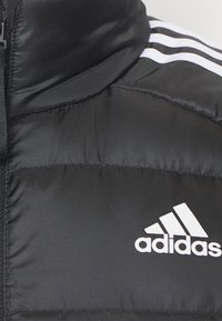 Černá padded bunda s bílým logem Adidas a třemi bílými pruhy na rameni, s předním zipem.