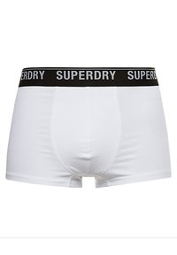 Boxer shorts blancos hechos de tejido elástico, con una cinturilla elástica negra de marca que lleva el texto "SUPERDRY" en gris en la parte frontal.