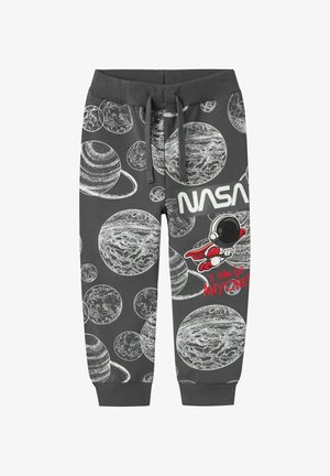 Un pantalon de jogging gris avec des motifs de planètes blanches, un astronaute et le logo "NASA". Comprend une taille à cordon et des chevilles élastiquées.