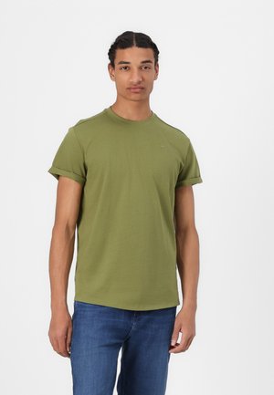 Olive green short-sleeve t-shirt made of soft cotton. Features a round neck and rolled cuffs, paired with blue denim jeans.