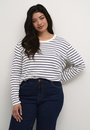Chemise blanche à manches longues avec des rayures horizontales bleu marine, associée à un jean en denim noir taille haute. Coupe douce et décontractée avec un col rond.