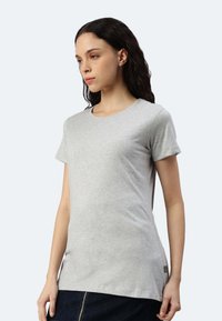 Maglietta grigia a maniche corte con scollo rotondo, realizzata in tessuto morbido, con una vestibilità slim e un piccolo etichetta del logo all'orlo.