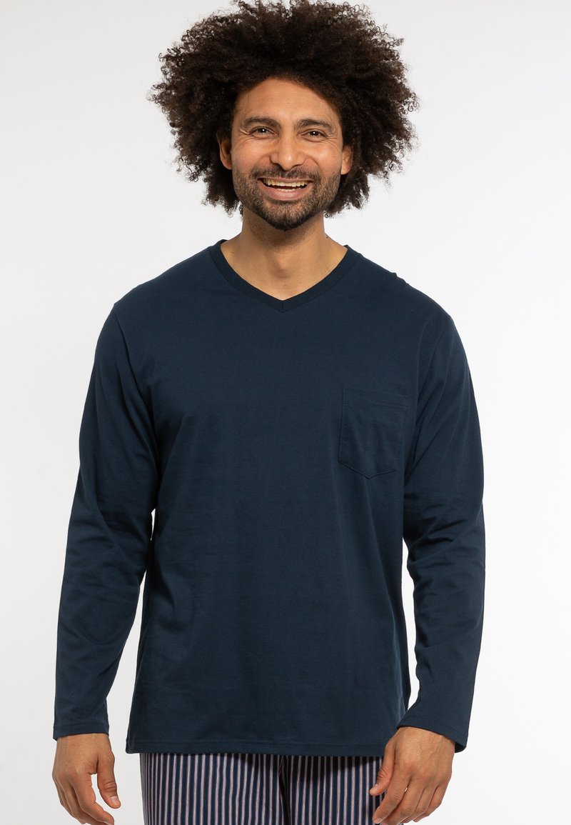 Navy long-sleeve t-shirt with a v-neck, featuring a small chest pocket and a soft cotton texture. Model also wears striped pajama pants.