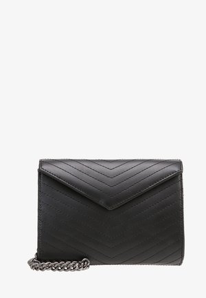 Pochette en cuir matelassé noir avec rabat en V et chaîne argentée visible en bas à gauche.