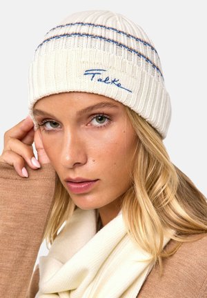 White knit beanie with ribbed texture, featuring blue and brown horizontal stripes, and "Falke" embroidered in blue on the front.