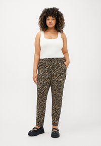 Bílý top na ramínka s čtvercovým výstřihem, černé kalhoty s leopardím vzorem, elastický pas, boční kapsy a černé robustní sandály.