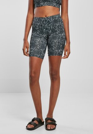 Shorts de cyclisme à motif noir et blanc en matériau extensible, taille mi-haute, associés à des sandales noires à bout ouvert.