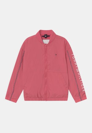 Chaqueta bomber rosa con cremallera, cuello acanalado, bolsillos laterales, finas rayas en las mangas y texto "Tommy Hilfiger" en la manga derecha.