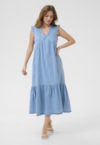 Gaiši zilas džinsa maxi kleita ar V veida kakla izgriezumu, volānu piedurknēm un pakāpenisku apakšējo malu, piedāvā brīvu piegriezumu un maigu tekstūru.