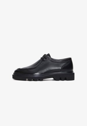Chaussures en cuir noir avec un bout rond, des détails cousus et une semelle épaisse et robuste présentant des rainures distinctives. Design à lacets simple.