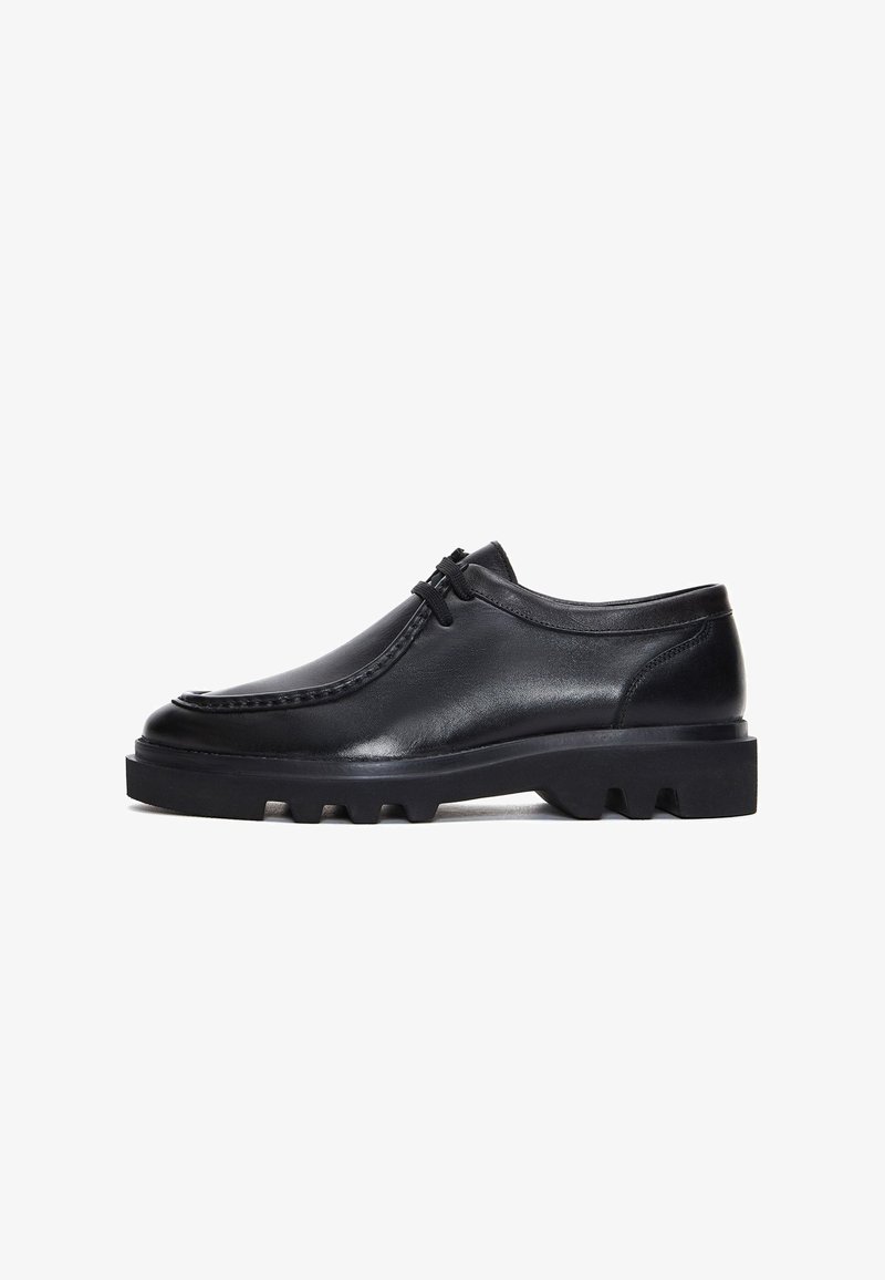 Schwarze Lederschuhe mit runder Spitze, genähten Details und einer dicken, robusten Sohle mit markanten Rillen. Schlichte Schnürsenkeldesign.