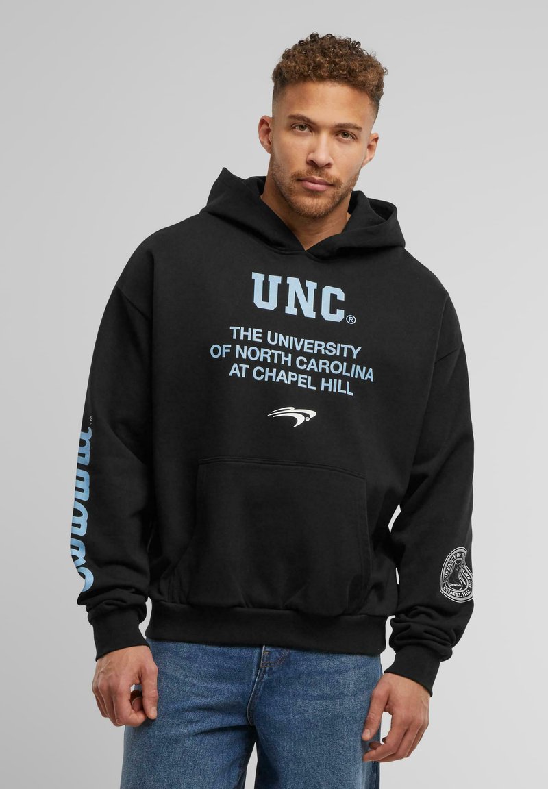 Zwarte katoenen hoodie met "UNC" in lichtblauwe tekst, een kangoeroe pocket en "North Carolina at Chapel Hill" in witte letters gedrukt.