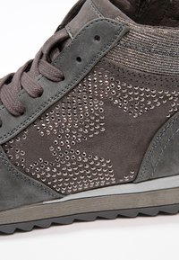 Šedé semišové tenisky se vzorem hvězdiček z malých kovových cvočků, s texturovaným látkovým akcentem a gumovou podrážkou pro lepší přilnavost.