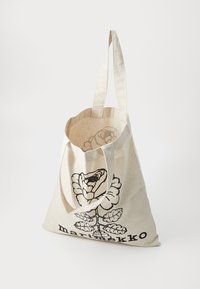 Canvas tote bag in light beige with a black floral design and logo. Features two sturdy handles and an open top for easy access.
